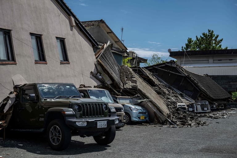 Cars are seen crushed under a collapsed house in Yatsushiro, Kumamoto prefecture on July 29, 2026, after an earthquake struck southwestern Japan the previous day. (Photo by Yuichi YAMAZAKI / AFP)