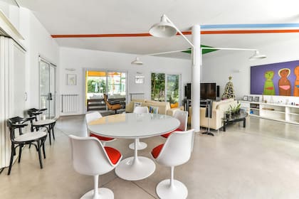 Las líneas de color atraviesan el cielo raso como rayos, iluminando un interiorismo blanco y contemporáneo. Atención a las luces que salen desde la columna, como si fueran faroles de calle.