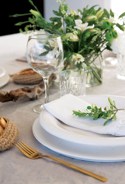Un detalle de la mesa, con cubiertos dorados y paneras de mimbre, tal como marca la tendencia