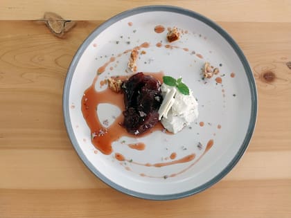 Cascos de membrillos en almíbar de cedrón, helado de roquefort, praline de frutos secos y flores de menta.