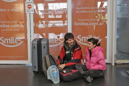 Catalina y Gerardo esperaban noticias de su vuelo, sentados en el piso