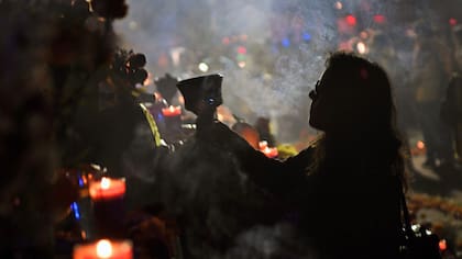 Una mujer coloca flores para recordar a sus seres queridos