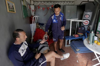 Matías Modolo, uno de los entrenadores que conforma la dupla técnica de Centro Español, le alcanza un mate a su compañero Sergio Orsini mientras ultiman detalles de la práctica en la utilería que le prestan en el club Huracán de San Justo