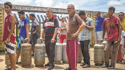 Cerca de los pozos donde se quema el petróleo, la gente hace fila por gas licuado.