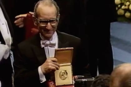César Milstein exhibe la medalla con el perfil de Alfred Nobel en el escenario de la Sala de Conciertos de Estocolmo, el tradicional lugar de entrega de todos los Premios Nobel, excepto el de la Paz.