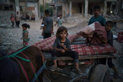 Chadi Nassir, de 7 siete años, se sienta en un carro tirado por un burro mientras su hermano, Mahmoud, lo carga con pertenencias recuperadas de su casa dañada en Beit Hanoun, en el norte de la Franja de Gaza, el domingo 13 de junio de 2021. (AP Foto/Felipe Dana)
