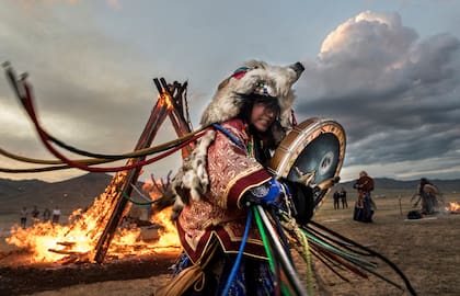 CHAMANES EN MONGOLIA Cada 22 de junio, los buu (chamanes mongoles) celebran el ritual de fuego que marca el solsticio de verano, en las afueras de Után Bator, la capital de Mongolia. Las actividades chamánicas resurgieron después de 70 años de prohibición bajo el régimen comunista y, desde 1992, están protegidas por la Constitución. La creencia es que los chamanes son elegidos por sus espíritus ancestrales para oficiar de puente entre el reino celeste y la vida terrenal. Emplean accesorios y vestimentas coloridas, que incluyen tocados, máscaras que cubren casi toda la cara –salvo los ojos– con el fin de entrar en trance para conectar con los espíritus. Se estima que hoy hay más de diez mil chamanes en Mongolia.