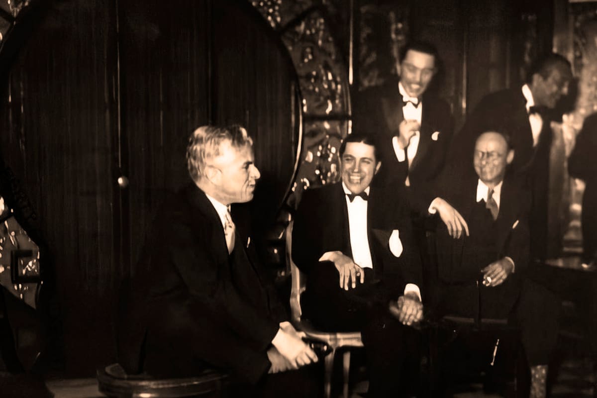 Chaplin representando un personaje y Gardel a carcajadas