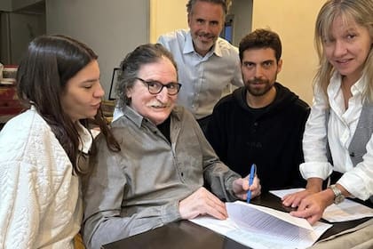 Charly García firmando con los abogados de Sony Music la publicación de su próximo álbum