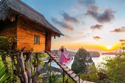Chica joven en los escalones de la casa en el árbol al amanecer en la isla de Nusa Penida, Bali en Indonesia