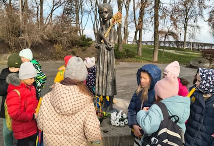 Chicos ucranianos rodean un monumento en Kiev que conmemora el Holodomor, la hambruna a la que Stalin sometió al país y que según distintas cifras mató hasta 4 millones de personas