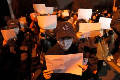 Los manifestantes sostienen papeles en blanco y corean consignas mientras marchan en protesta en Pekín, el domingo 27 de noviembre de 2022