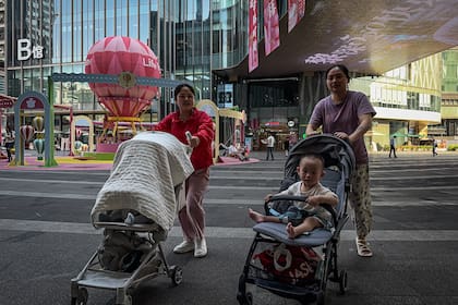CHONGQING, CHINA - MAY 20: Women push strollers with young children through a commercial plaza featuring colorful decorations and play structures, including hot air balloon-themed displays, on May 20, 2025 in Chongqing, China. As concerns over declining birth rates persist, Chinese cities are increasingly investing in child-friendly infrastructure to encourage family-oriented lifestyles and support population growth initiatives. (Photo by Cheng Xin/Getty Images)