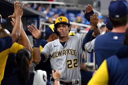Christian Yelich (22), de los Cerveceros de Milwaukee, es felicitado después de anotar en contra de los Marlins de Miami durante la novena entrada del juego de béisbol, el viernes 13 de mayo de 2022, en Miami. (AP Foto/Jim Rassol)