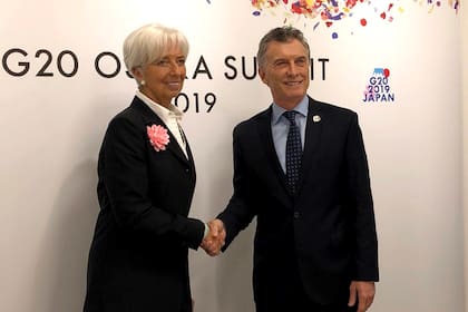Christine Lagarde, bien clásica, con traje negro, camisa blanca y flor rosada en el ojal.