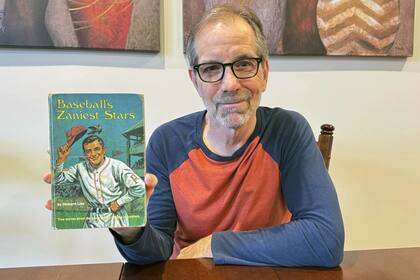 Chuck Hildebrandt, de Chicago, sostiene el libro "Las estrellas más estrafalarias del béisbol" el 10 de diciembre de 2024, que debía regresar a la biblioteca 50 años antes (Terrie Wendricks/AP)