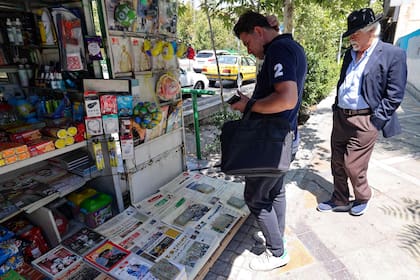 Ciudadanos miran los diarios en un kiosko de Teherán, un día después del ataque al escritor Salman Rushdie en Nueva York. (Photo by ATTA KENARE / AFP)