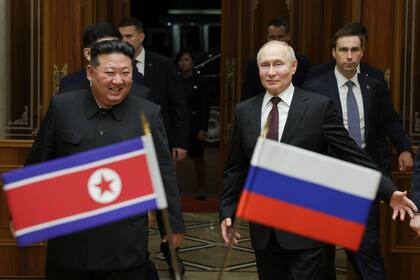 Ciudadanos norcoreanos, con retratos del presidente de Rusia, Vladímir Putin, y flores, saludan la comitiva del mandatario ruso y del líder del país, Kim Jong Un, as su paso por una calle de Pyongyang, Corea del Norte, el 19 de junio de 2024. (Gavriil Grigorov, Sputnik, Kremlin Pool Foto vía AP)