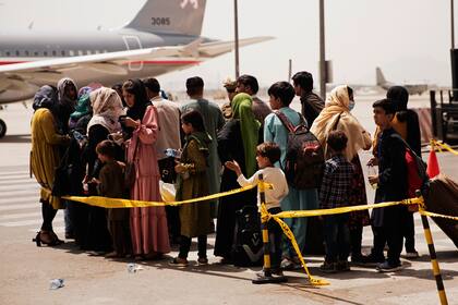 Civiles se preparan para abordar un avión en el aeropuerto internacional Hamid Karzai en Kabul, Afganistán