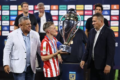 Claudio 'Chiqui' Tapia acaba de entregar el trofeo del torneo Clausura al capitán, Santiago Ascacibar; el presidente de la AFA que sancionó a Estudiantes terminó premiando como campeón al club pincharrata.