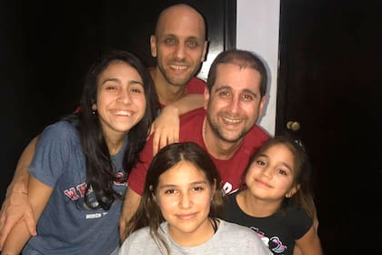 Claudio junto a Fernando, su pareja, y sus tres hijas en su casa en Rosario