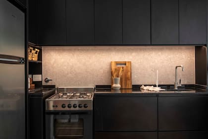 Cocina contenida por la caja negra que conforma el mueble (Estudio Vara), hecho con melamina negra de Egger. Mesada de mármol ‘Brasil’ con pileta (Johnson Acero), grifería monocomando ‘Gourmet’ (Piazza) y alzada en porcelanato esmaltado.