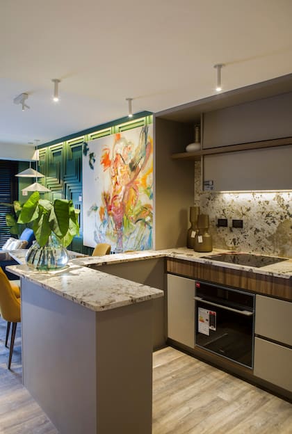 La cocina acompaña el desarrollo del departamento con el derrame de la piedra de la mesada y la barra en una mesa más baja.