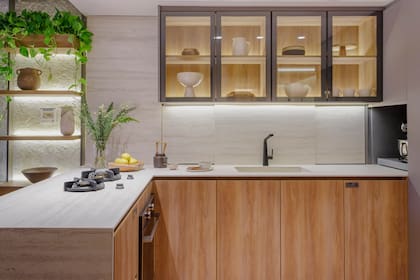 Bajomesada en melamina 'Blend Scotch' resistente a la humedad de Faplac, ejecutada por Carpintería Canessa. Mesada en Puraprima Travertino Navona (De Stefano y Cavatori). Hornallas Pitt cooking (De Stefano). Horno (Teka). Grifería 'Aromo' en negro (FV). A la izquierda, mueble en Rauvisio Noir 'Trench Coat' (Rehau) con estantes móviles. Zócalos y herrajes (Rehau). Vajilla (Casa Clara).