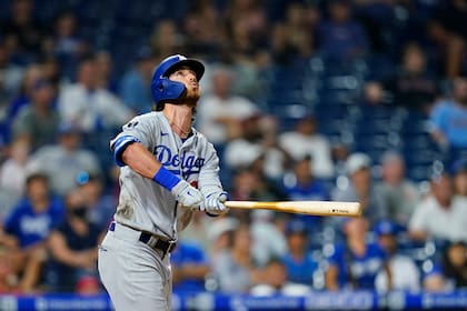 Cody Bellinger, de los Dodgers de Los Ángeles, observa la pelota al conectar un jonrón en el noveno inning del juego del miércoles 11 de agosto de 2021, ante los Filis de Filadelfia (AP Foto/Matt Slocum)
