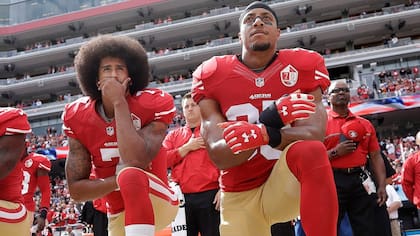 Colin Kaepernick, a la izquierda, en su clara posición de reclamo: de rodillas en el fútbol americano