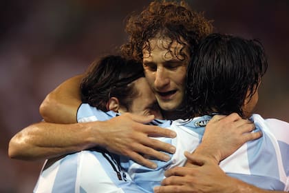 Coloccini, con la camiseta de la selección nacional, y el abrazo con Lionel Messi; cerca de los 40 años, el defensor le puso fin a su carrera