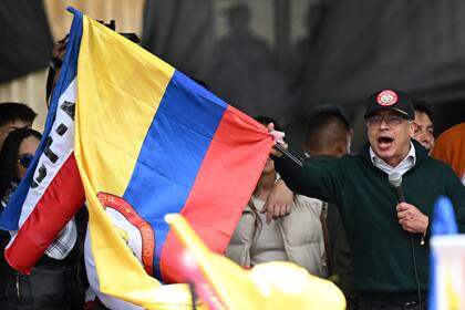 Colombian President Gustavo Petro waves a national flag as he delivers a speech during a May Day (Labor Day) rally in Bogota on May 1, 2024. Colombian President Gustavo Petro said Wednesday his country will sever diplomatic ties with Israel, whose leader he described as "genocidal" over its war in Gaza. (Photo by Raul ARBOLEDA / AFP)