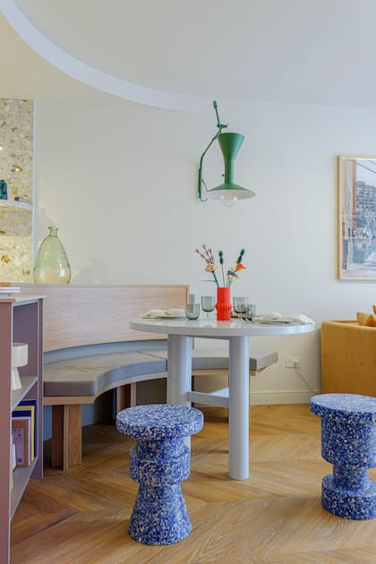 La mesa laqueada en celeste brillante y los bancos de plástico roto moldeado son de la marca de Sara, Par en Par. Lámpara verde (Lumishop para Par en Par). Banco curvo (Moi muebles). Almohadón (Lote Propio). Los platos pintados a mano son de cerámicas BOYLE para Par en Par y los individuales bordados, de Violeta Bajas para Par en Par. Copas, vasos y cubiertos (Retoño).