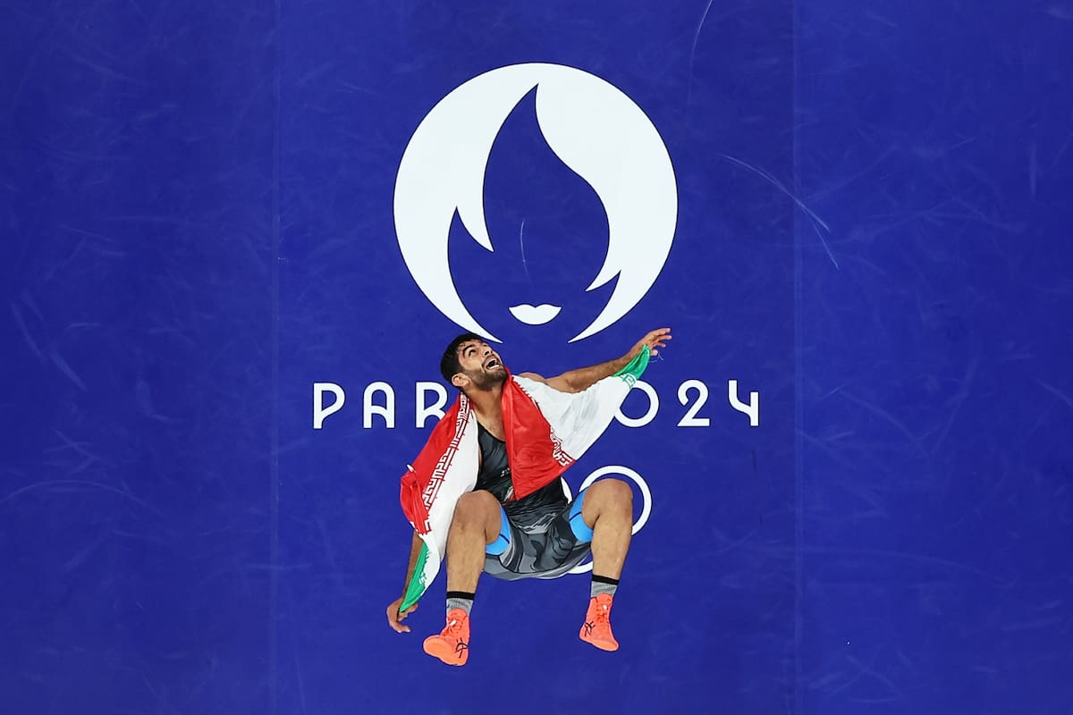 Comentario atribuido a Paul Gilham, director global de deportes en Getty Images Esta foto, capturada por el fotógrafo de Getty Images Rob Carr con una de nuestras cámaras robóticas, muestra a Mohammadhadi Saravi del equipo iraní envuelto en la bandera de su país. La imagen refleja no solo el esfuerzo y la dedicación invertidos en llegar a este punto, sino también la inmensa alegría y el orgullo de representar a su nación en los Juegos Olímpicos de París 2024. El contraste entre la energía vibrante del competidor y la serenidad del fondo azul, junto con el icónico logo de los juegos, crea una imagen poderosa y emotiva que encapsula el espíritu olímpico.