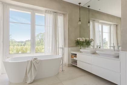 Como la bañera exenta está junto a la ventana, instalaron una cortina de gasa más gruesa. Vanitory suspendido con mesada de mármol (Muliere-Padilla) y bachas de apoyo (Duravit).