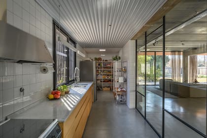 Como mobiliario, eligieron un bajomesada y agregaron espacio de guardado extra con una estantería que hace de despensa a la vista.
