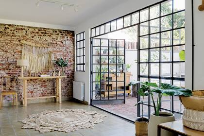 Complementaron la pared con piezas de madera y fibras naturales, porque querían un efecto rústico, no industrial. Obra realizada con hilos de seda natural y fibras (Cris Codern). Consola (Casa Perri). Lámpara (D A Iluminación).