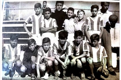 Con balón en mano, Juan Pablo, padre de Carlos, posa junto a sus dirigidos infantiles. Los convocaba en potreros y los llevaba a jugar contra las divisiones inferiores de Racing y otros clubes grandes. Muchos de estos chicos lograron impresionar a sus rivales y entraron formalmente en esos equipos