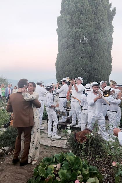 Con el atardecer de fondo, los recién casados bailan al ritmo de la banda de músicos.