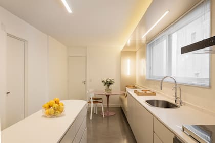 Con el mismo material de los muebles bajomesada –madera laqueada en tono 'Calcáreo' (Alba)–, el Estudio diseñó una estructura de techo y sillón que abarca al comedor diario.