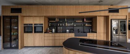 Con generoso y discreto espacio de guardado, el mueble de cocina (Muc Muebles) se apoya en una de las diagonales de la casa. La bacha, las mesadas y el nicho del mueble exento se revistieron en Dekton ‘Domoos’ (Canteras del Mundo), que crea un lindísimo contraste con la madera de incienso.