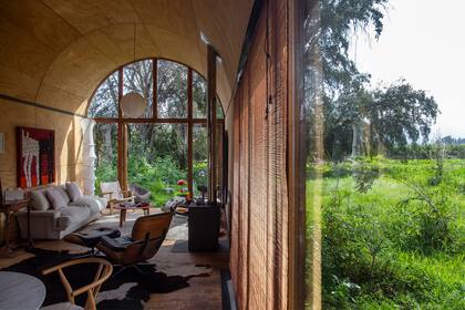 Con grandes ventanales de suelo a techo, el paisaje se convierte en una extensión de la casa, proporcionando una vista panorámica y el ingreso de luz natural. Sofá diseñado por el decorador chileno Mario Matta.