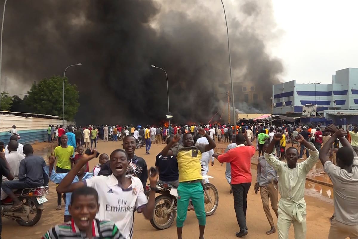 Con la sede del gobierno ardiendo de fondo, partidarios de los soldados amotinados se manifiestan en Niamey, Níger, el 27 de julio de 2023. (AP Foto/Fatahoulaye Hassane Midou)