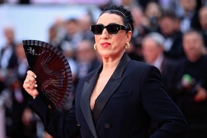Con lentes de sol y abanico, la española Rossy de Palma llegó a la cita con un vestido escote en “V”, tipo blazer con solapa satinada y hombreras, firmado por Anthony Vaccarello, íntimo amigo de la actriz y director creativo de Saint Laurent.