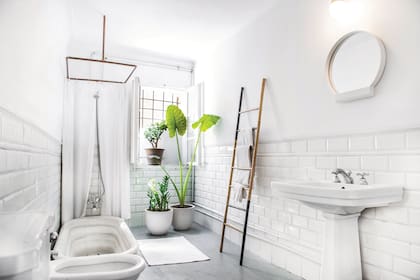 Con piso de cemento alisado y revestimiento de azulejos blancos, el baño tiene un lavatorio de pie que los chicos rescataron de una obra cuya iluminación realizaron.