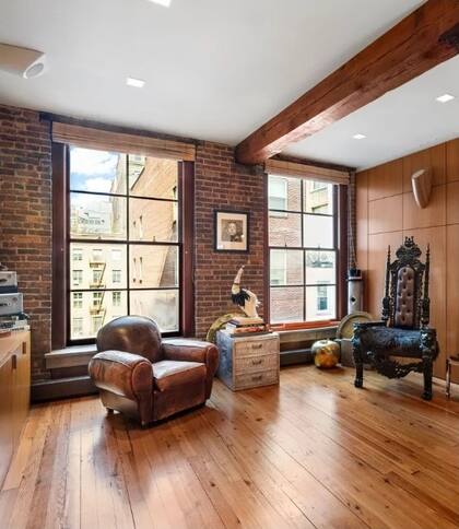 Con pisos de madera y ventanales de gran tamaño, el living destaca por su amplitud, luminosidad y la presencia de elementos originales de la construcción