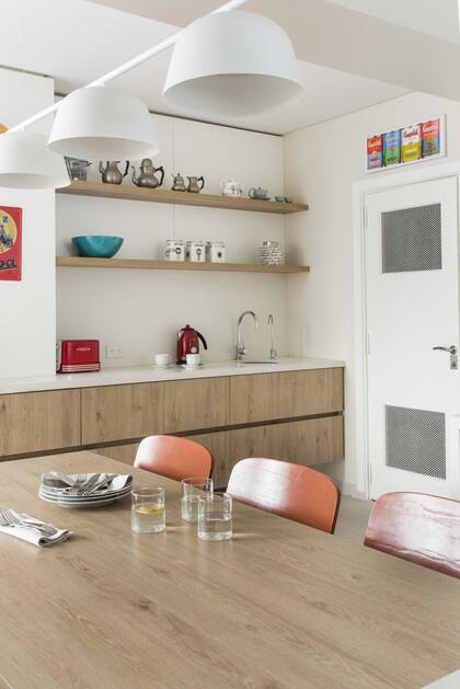 Con reforma e interiorismo de la arquitecta Patricia Daiez, esta cocina tiene un barral con tres pantallas de Via Luce sobre la mesa acompañada por sillas de El Yeite.