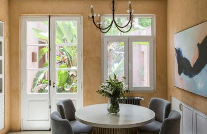 Con salida al patio central, el comedor diario tiene mesa de microcemento y sillas tapizadas en pana. El cuadro es obra de la dueña de casa, Verónica del Olmo (Il Vero Art).