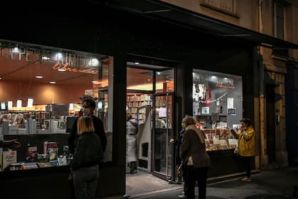 Con tapabocas, la gente hace cola frente a una librería para recolectar libros, en París, en el segundo día de un segundo cierre general nacional