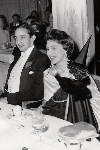 Con un vestido
strapless y gargantilla
de diamantes,
Margarita sostiene
en brazos una bruja,
acompañada por
Billy Wallace (fue
su prometido hasta
que ella rompió
el compromiso
cuando él le confesó
una infidelidad)
durante la fiesta
de Halloween
celebrada en el hotel
Dorchester, en 1957.